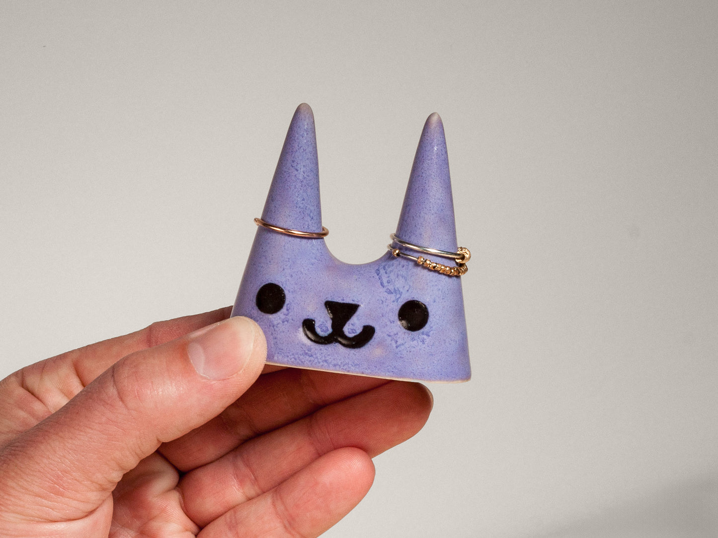 Hand holding purple cat-shaped ceramic ring holder 