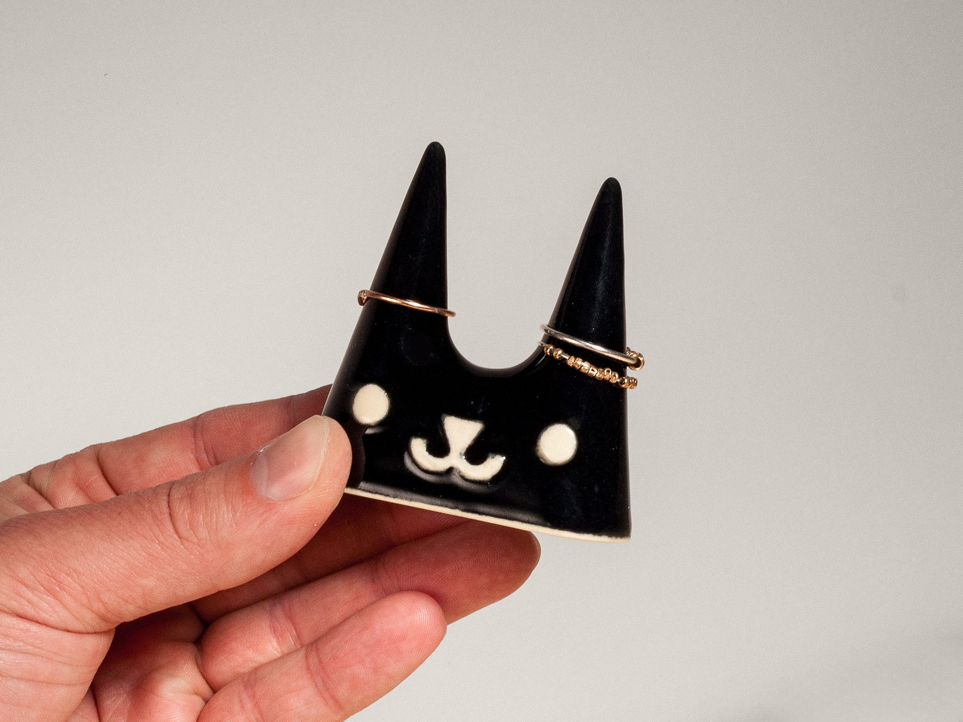 Hand holding black cat-shaped ceramic ring holder