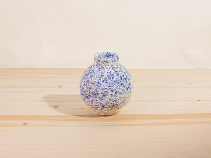 Blue and white speckled ceramic vase on a wooden surface with a plain background
