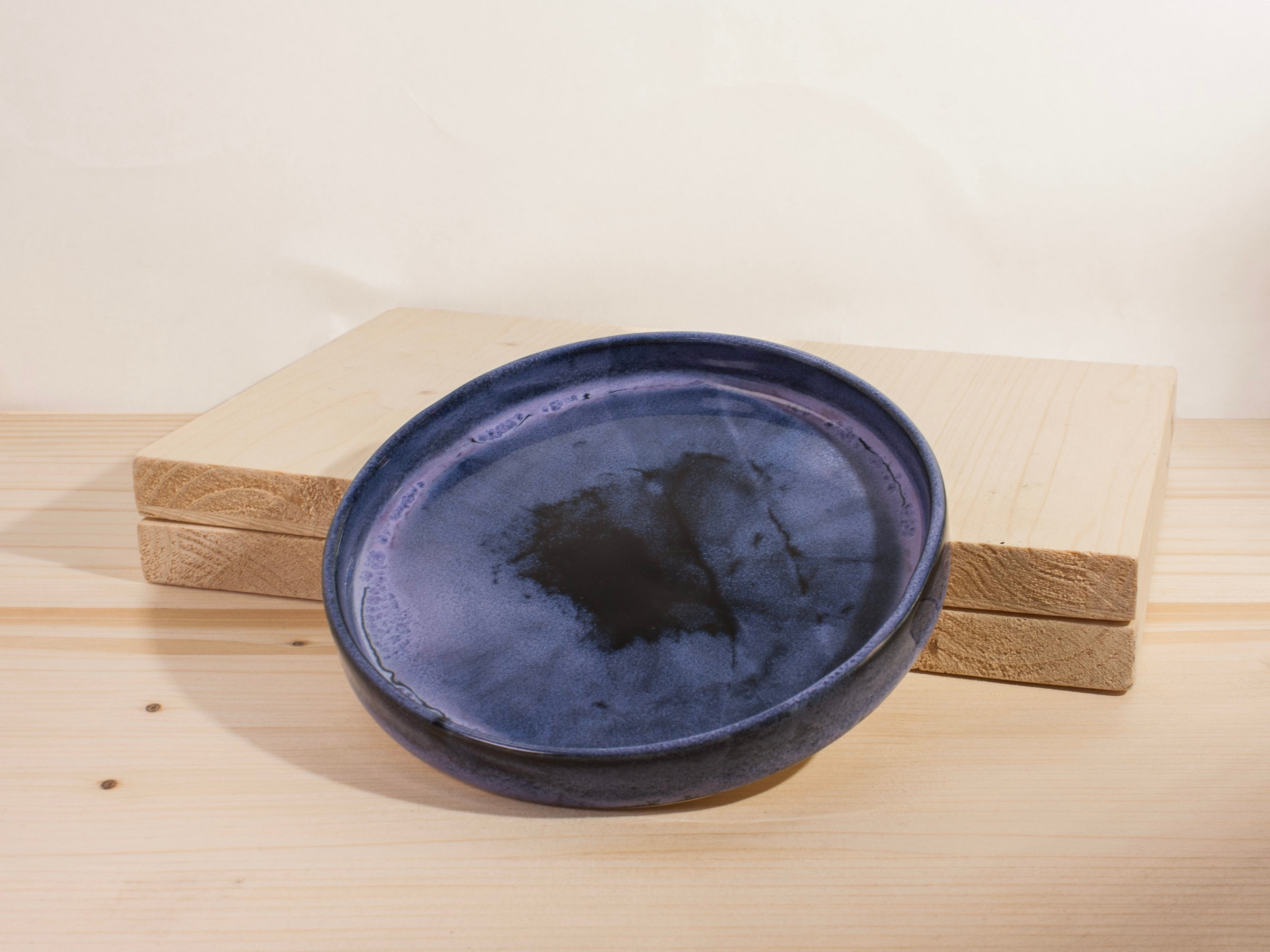 Dark purple ceramic plate on a wooden surface with a white background