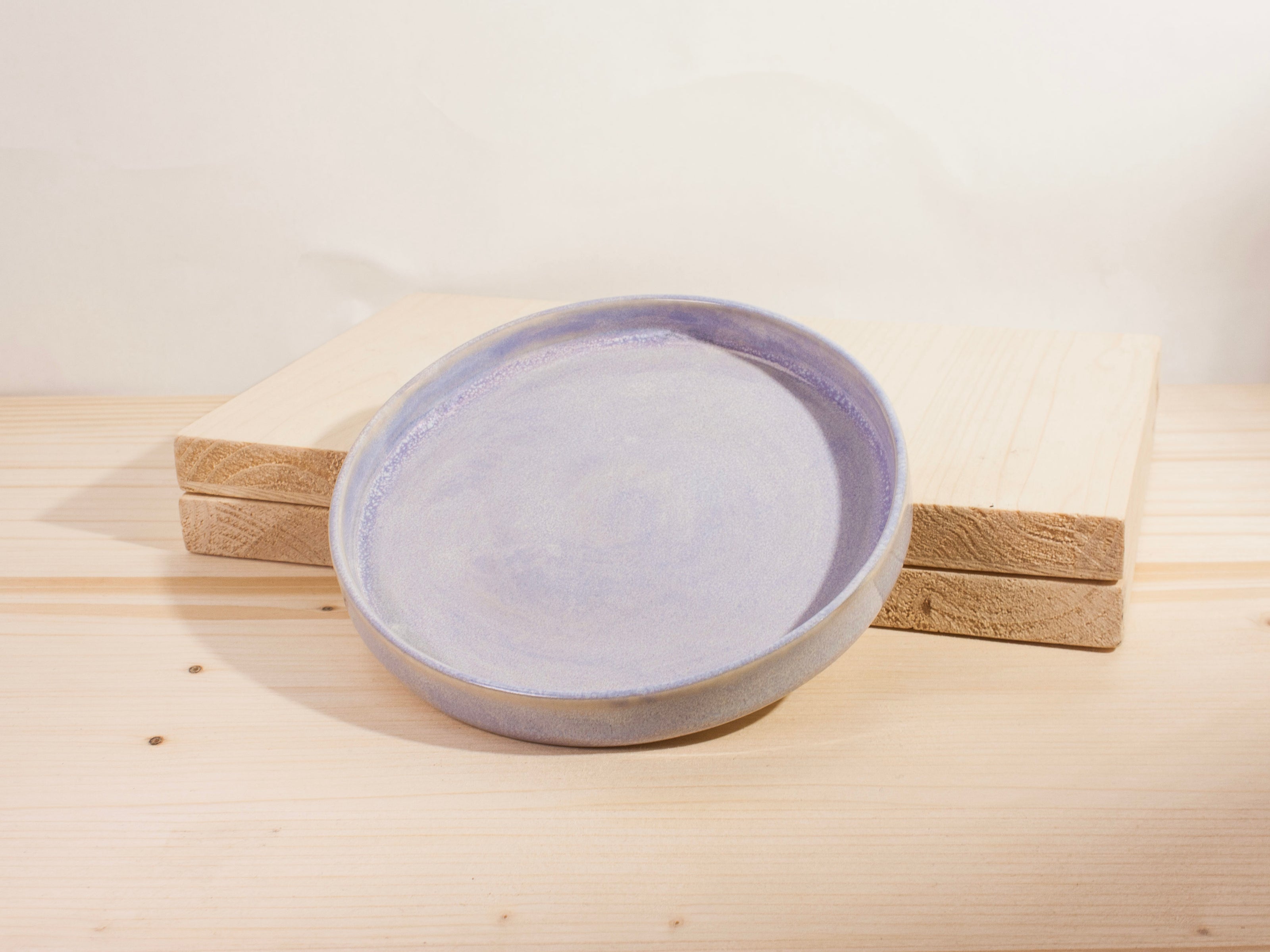 Round ceramic plate with purple interior on a wooden surface