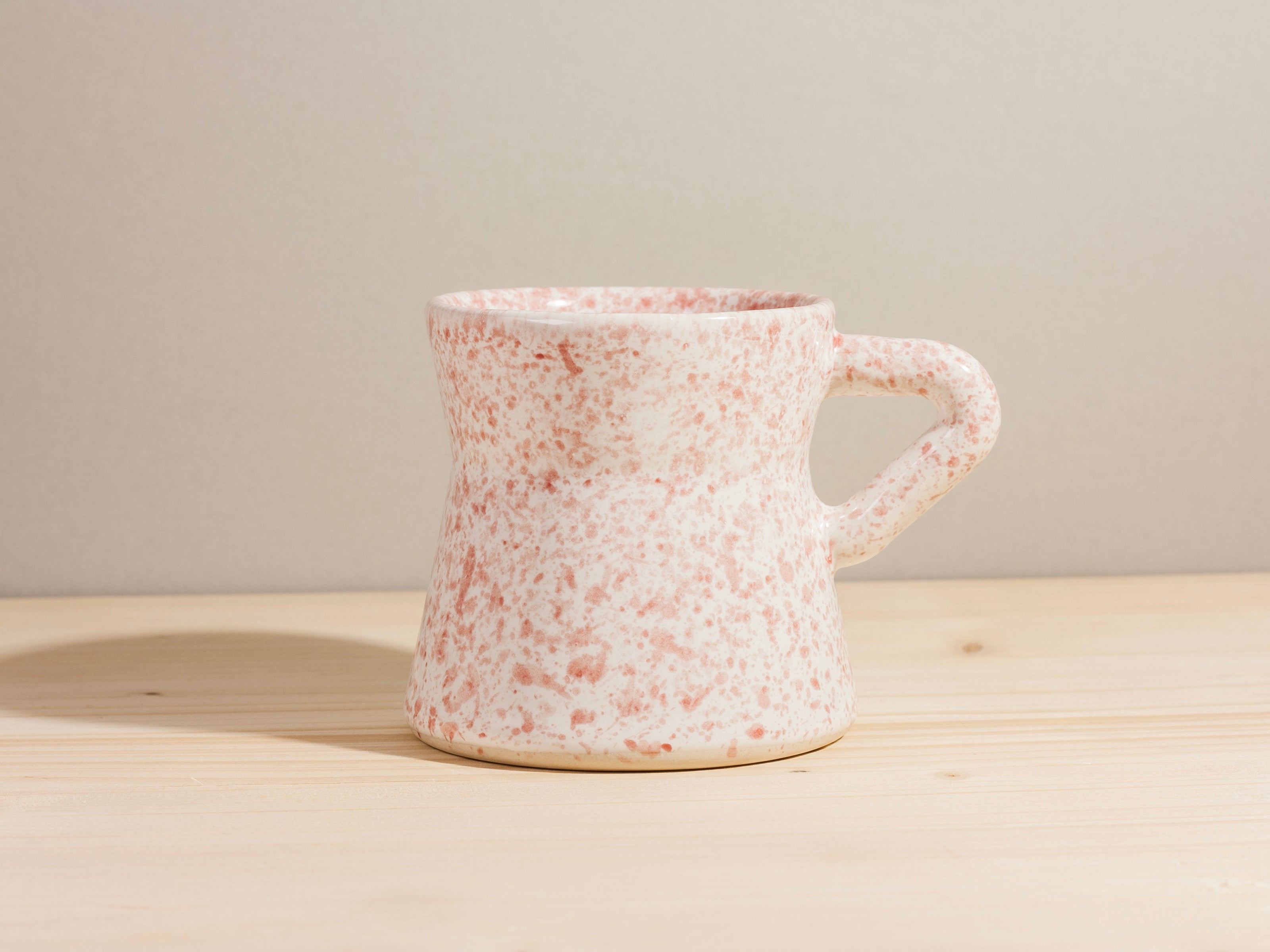 Speckled ceramic mug on a wooden surface with a neutral background