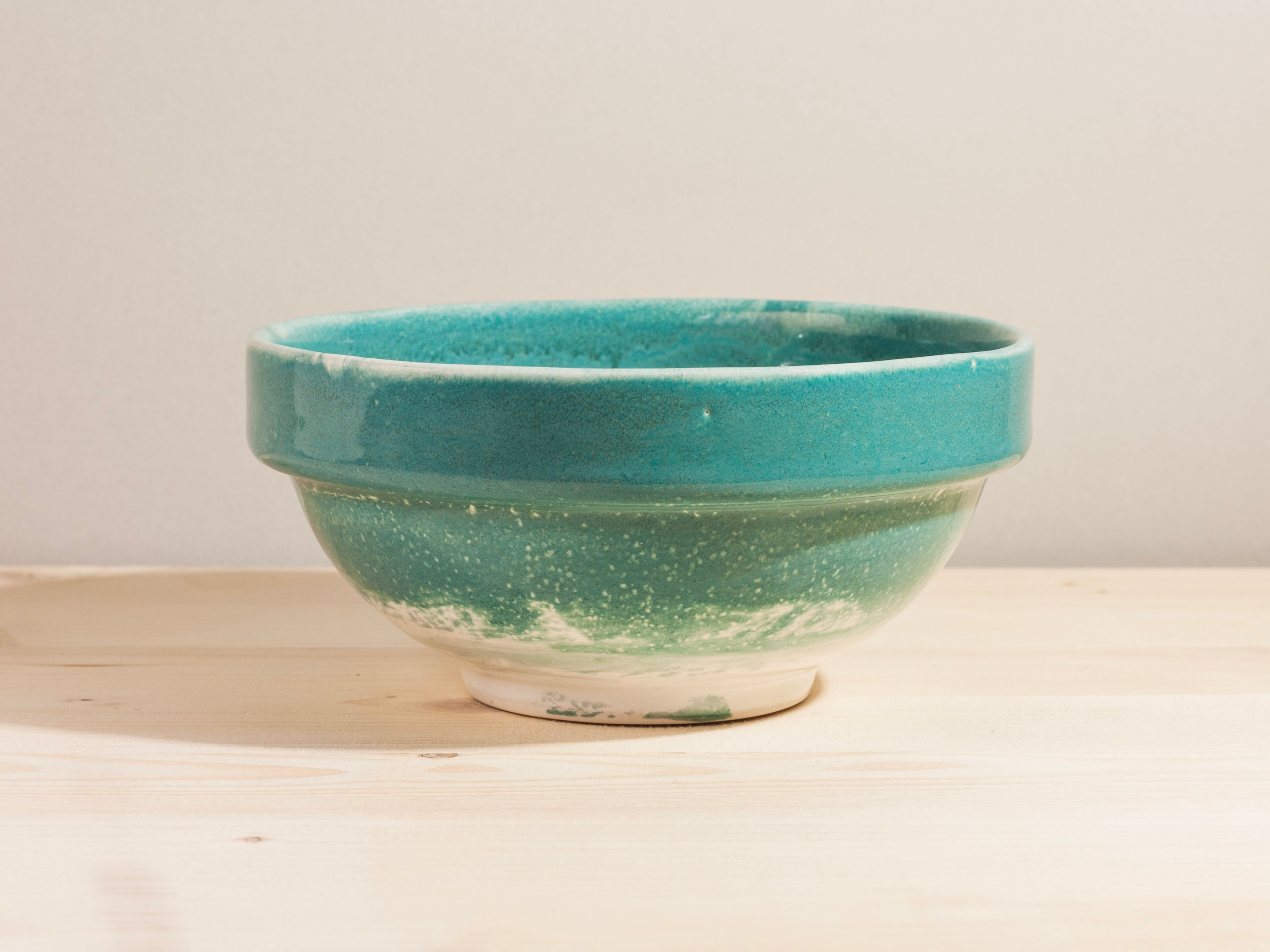 Turquoise ceramic bowl on a wooden surface with a neutral background