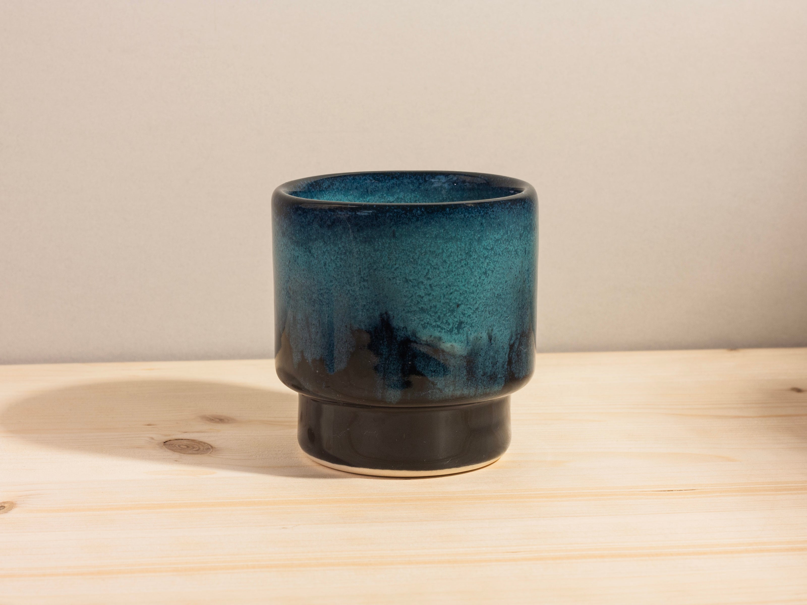 Blue ceramic cup on a wooden surface with a neutral background