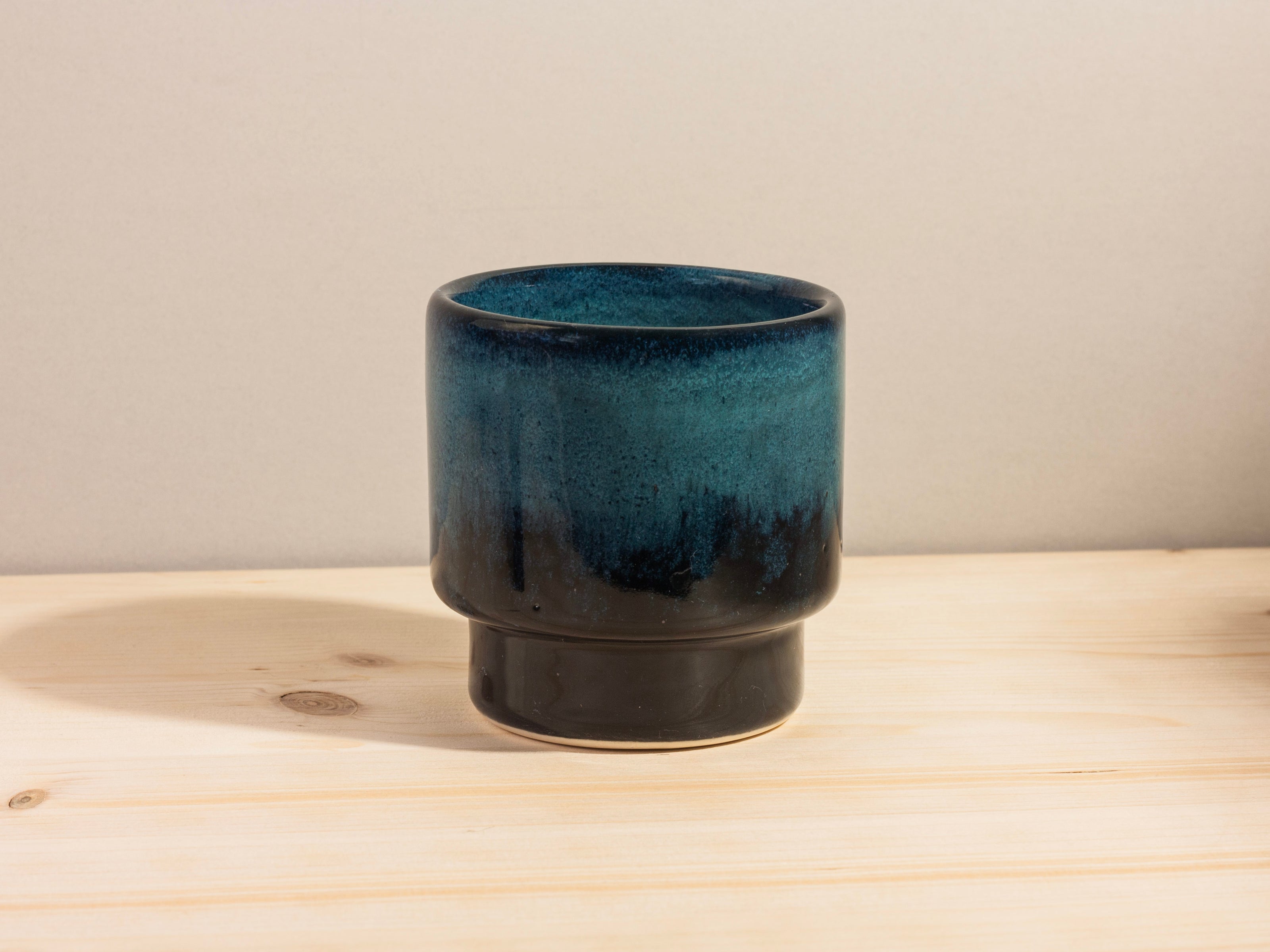 Blue ceramic cup on a wooden surface with a neutral background