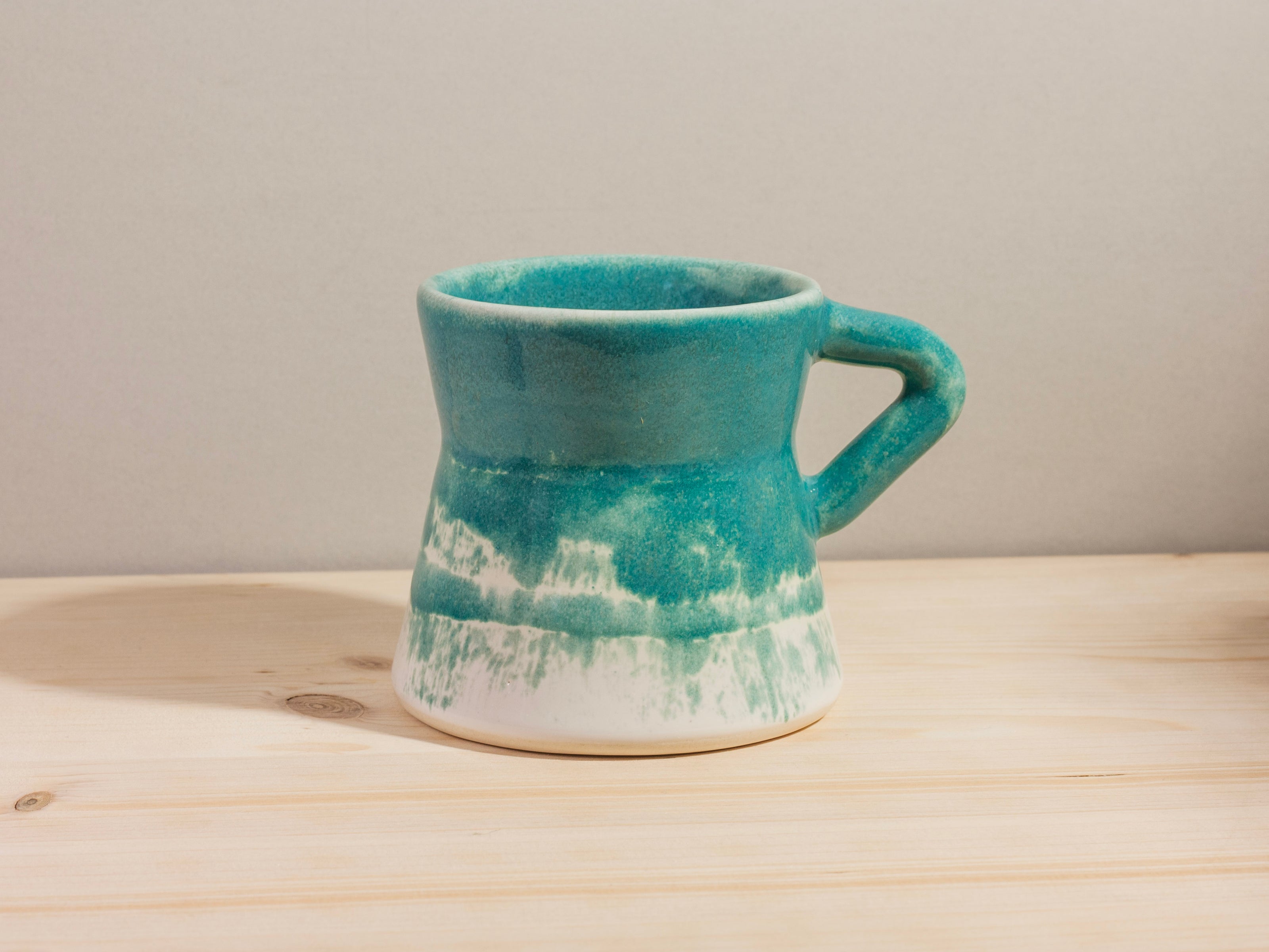 Turquoise ceramic mug on a wooden surface
