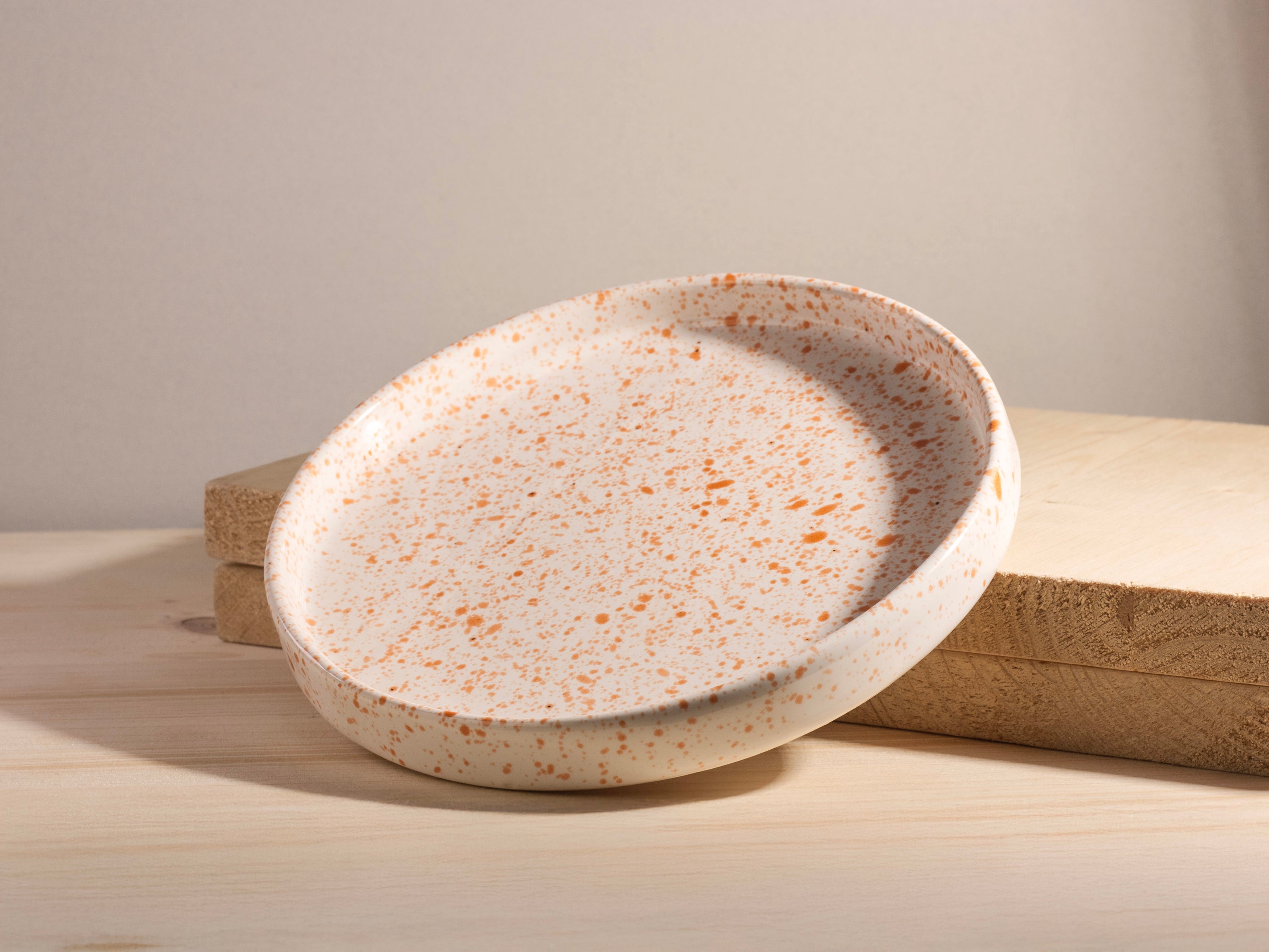 Speckled ceramic plate on a wooden surface with a neutral background