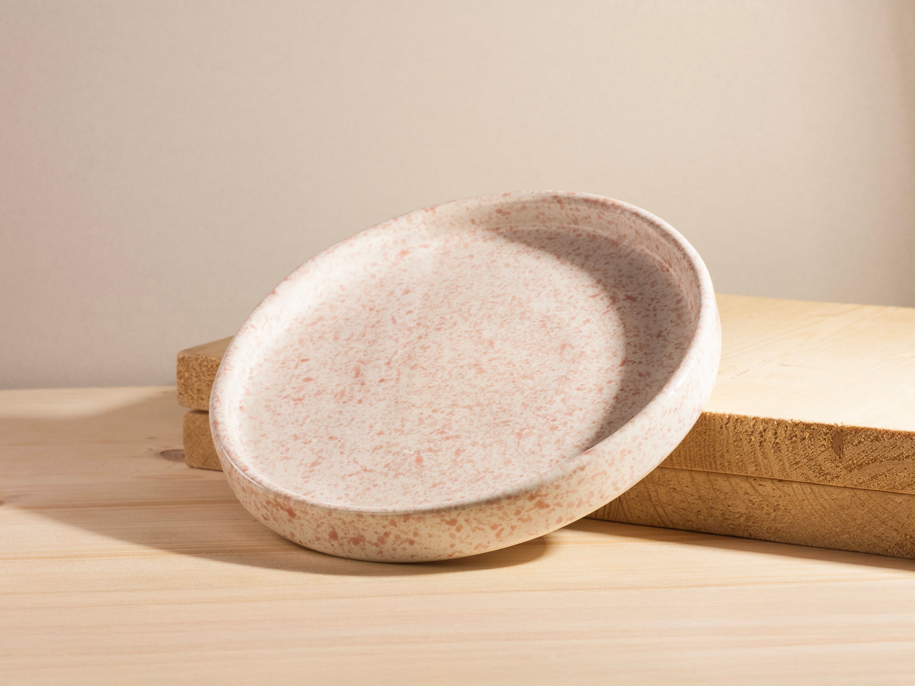Speckled ceramic bowl on a wooden surface with a neutral background