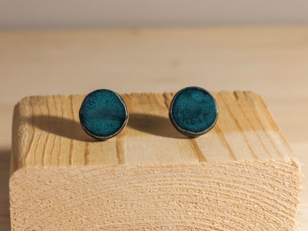 Pair of blue round earrings on a wooden block