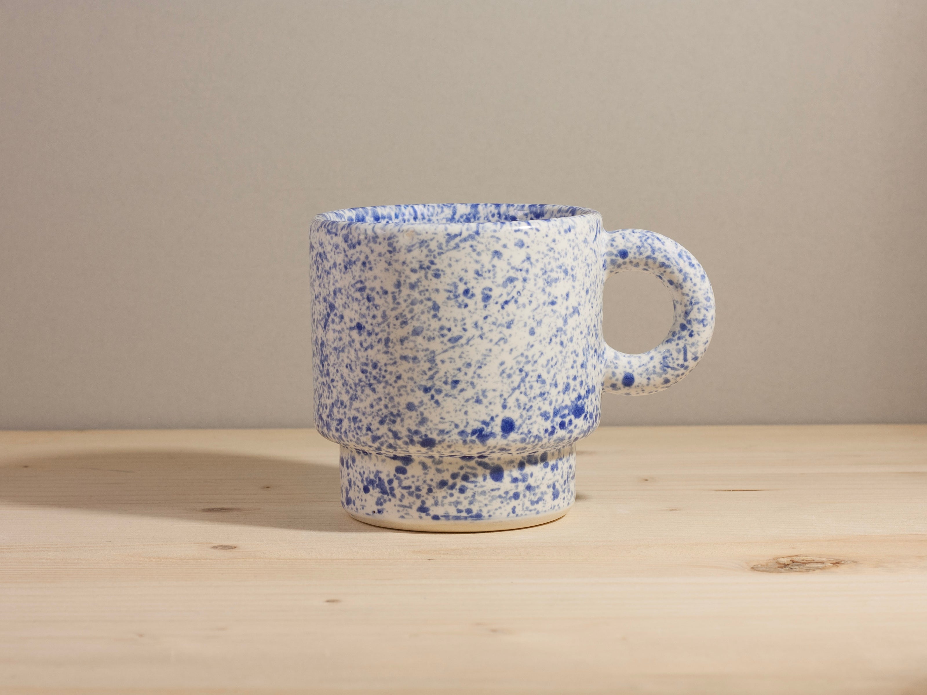 Speckled blue and white ceramic mug on a wooden surface with a neutral background