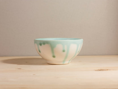 Ceramic bowl with green and white glaze on a wooden surface