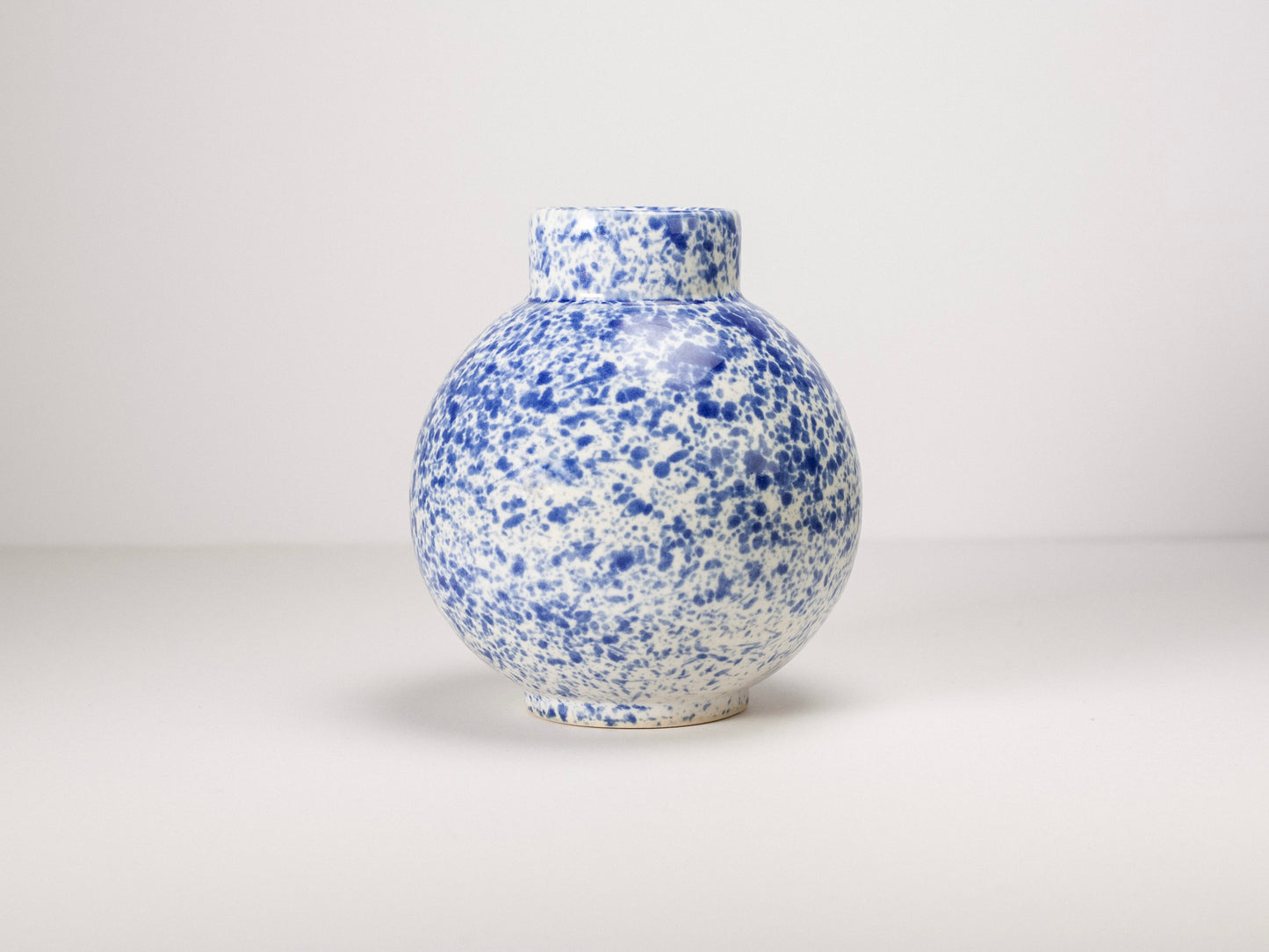 Speckled blue and white ceramic vase on a light gray background