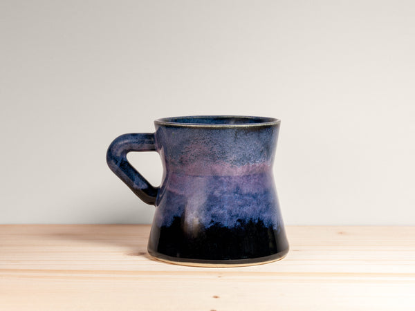 Blue ceramic mug on a wooden surface with a light gray background